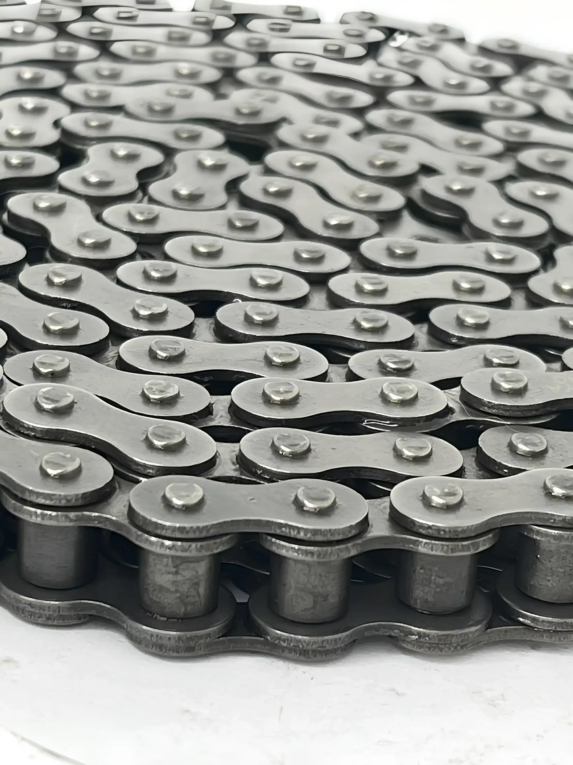 Renold SD Roller Chain Simplex-BS shop bearingsspecialist | E-Shop Bearings Specialist Close-up of overlapping silver chain links with riveted pins, forming an interlocking pattern.